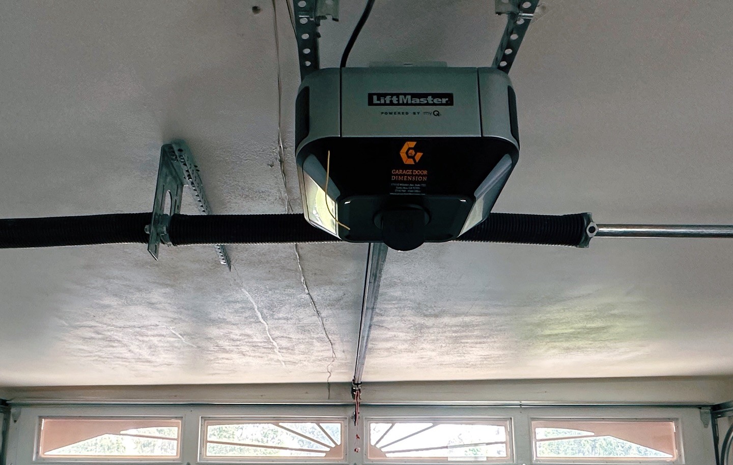 LiftMaster garage door opener installed in a residential garage, featuring Garage Door Dimension branding, showcasing advanced technology for efficient operation.