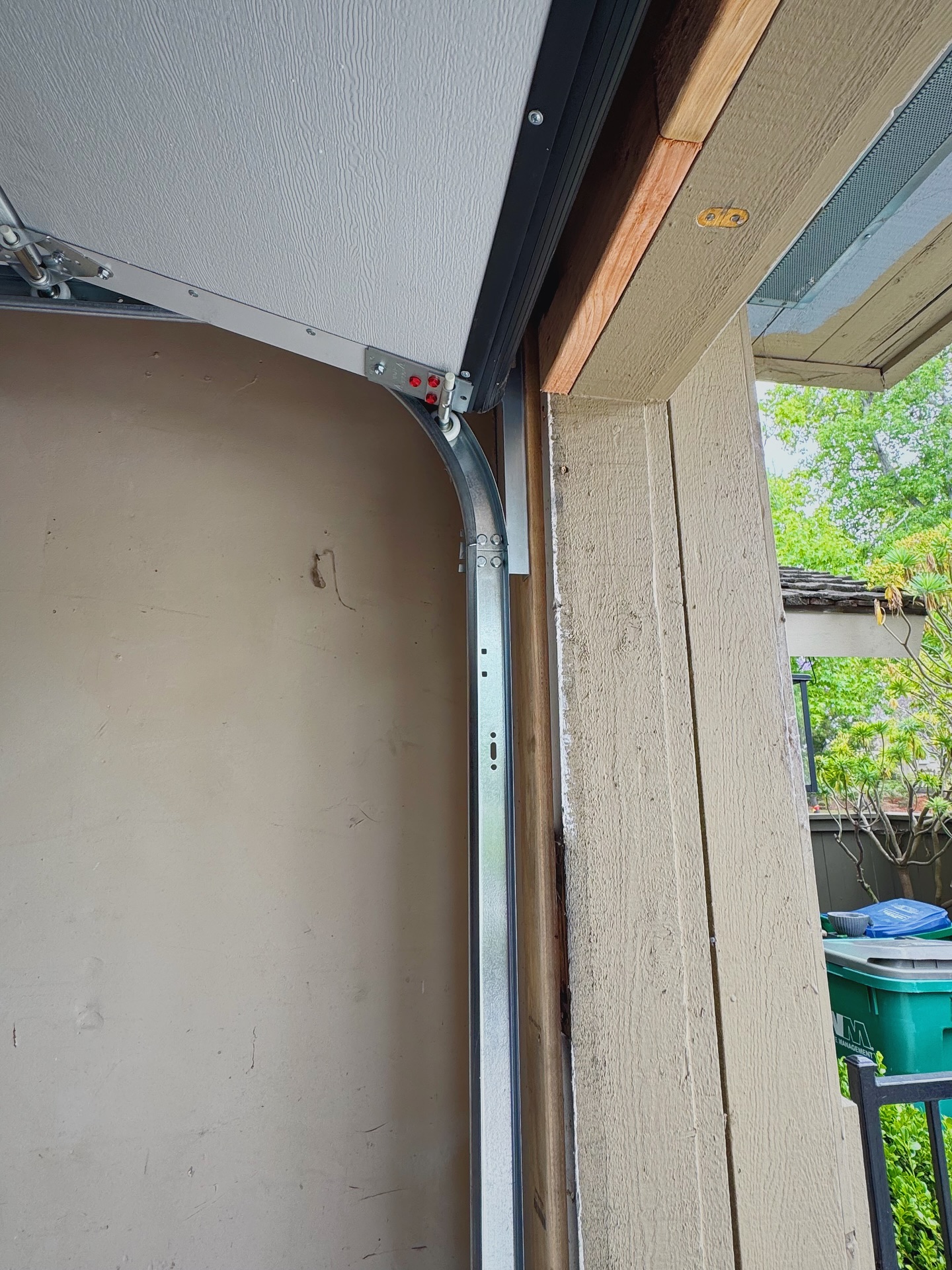 Garage door track system installed in a residential garage, featuring metal tracks and rollers, illustrating the alignment and support for smooth door operation.