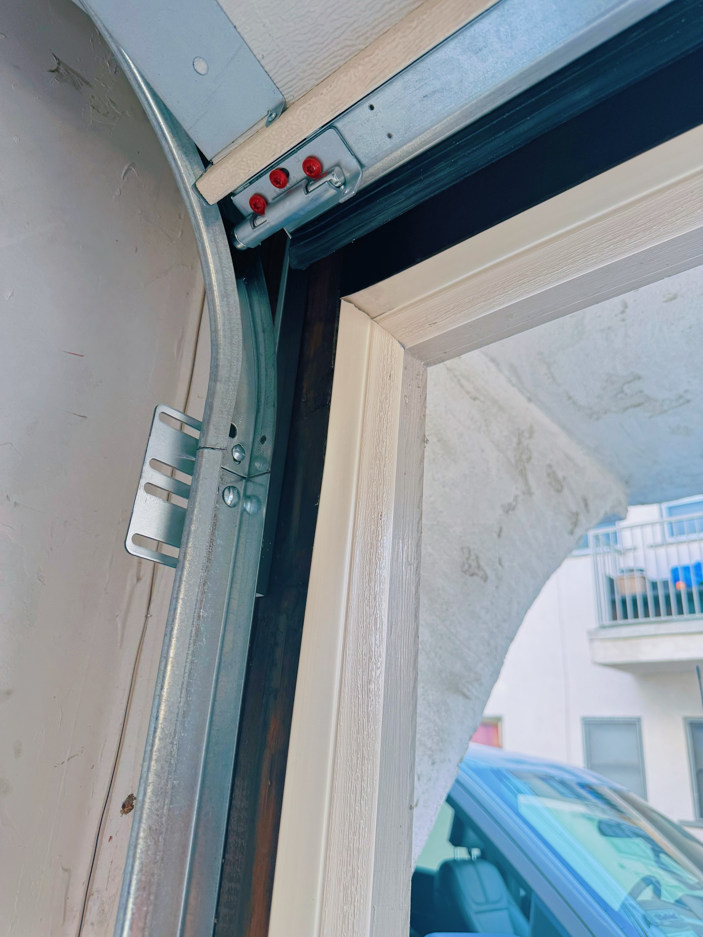 Close-up of a garage door track system featuring steel components, alignment brackets, and a curved track section, illustrating installation details relevant to residential and commercial garage door setups.