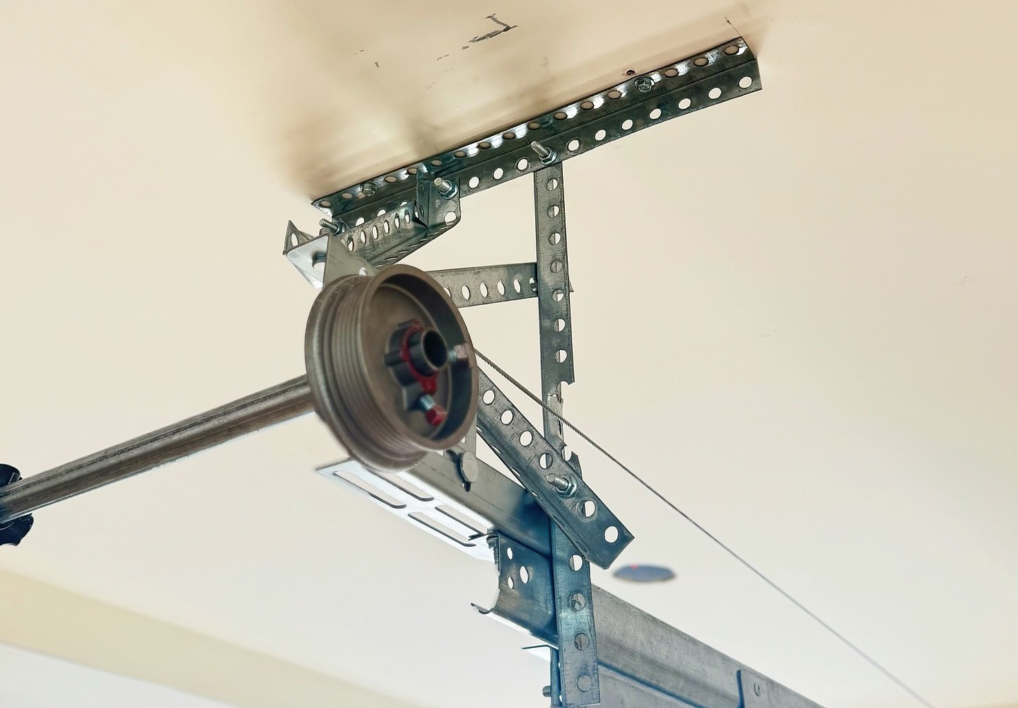 Garage door cable system featuring a pulley and metal brackets, illustrating components essential for safe and reliable garage door operation.