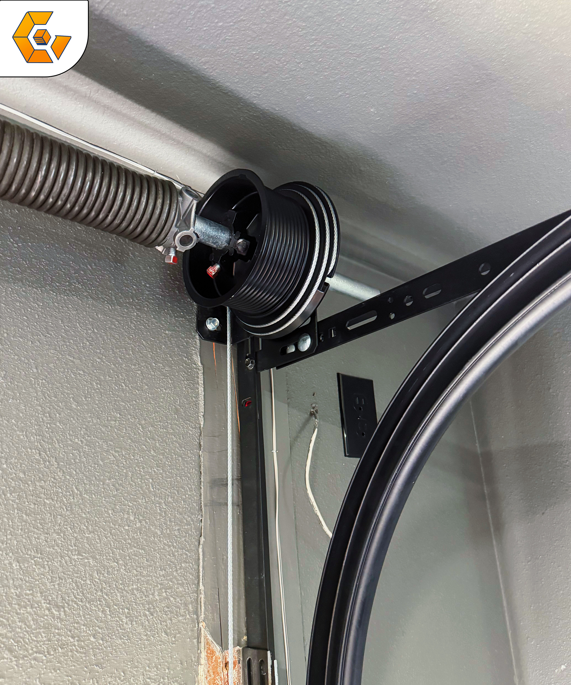 Garage door cable system with a pulley and tension spring, showcasing high-quality materials for safe and reliable operation, relevant to garage door repair services.