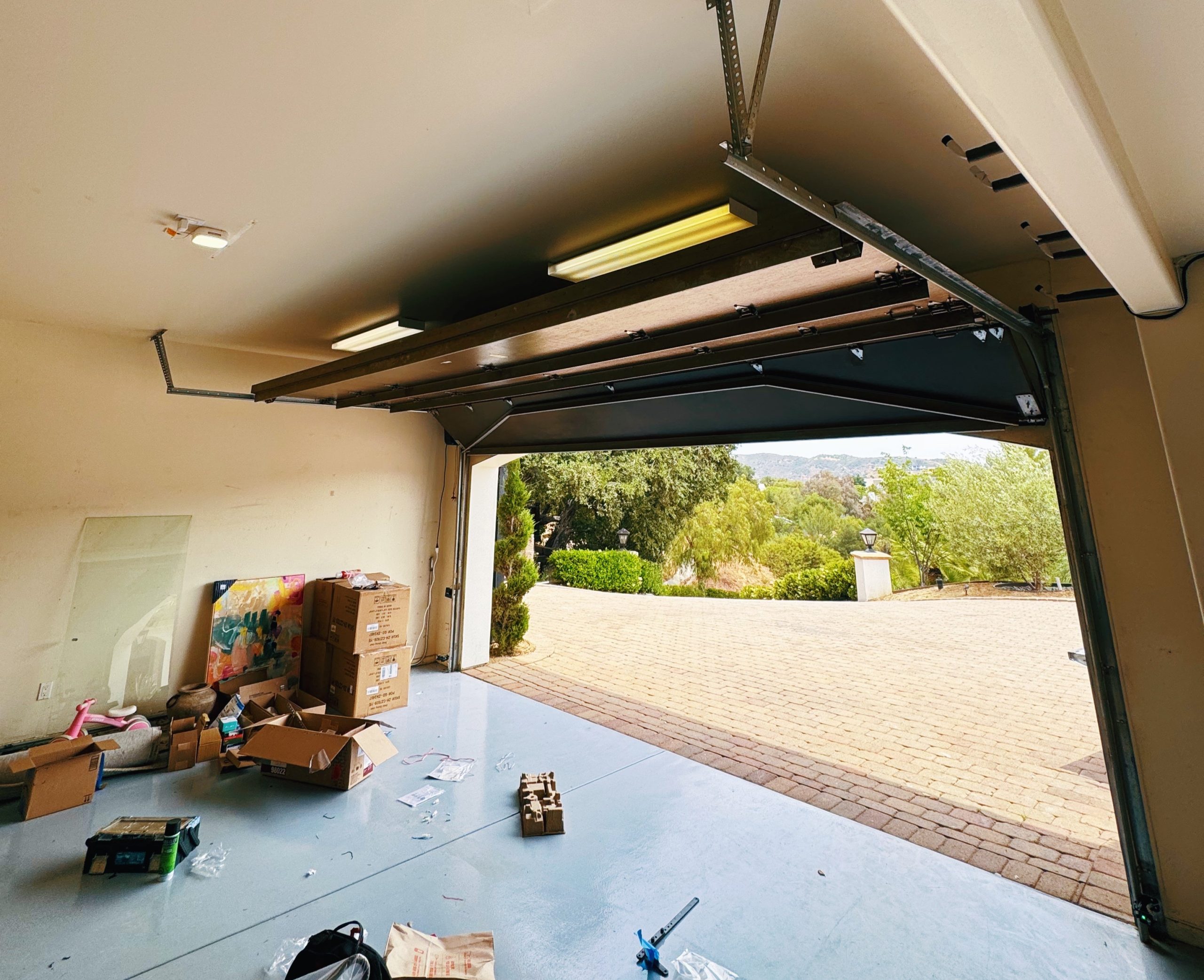 Garage interior with partially open garage door, showcasing tracks and surrounding clutter, emphasizing potential issues like misalignment or blockage affecting door operation.