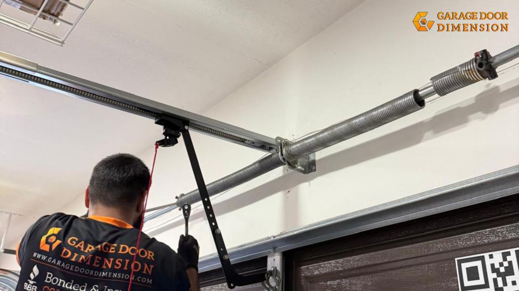 Technician adjusting torsion spring on garage door system inside residential garage