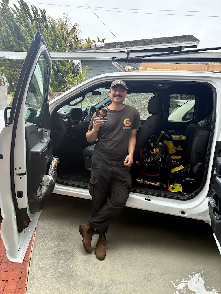A garage door technician posing in front of a service truck.